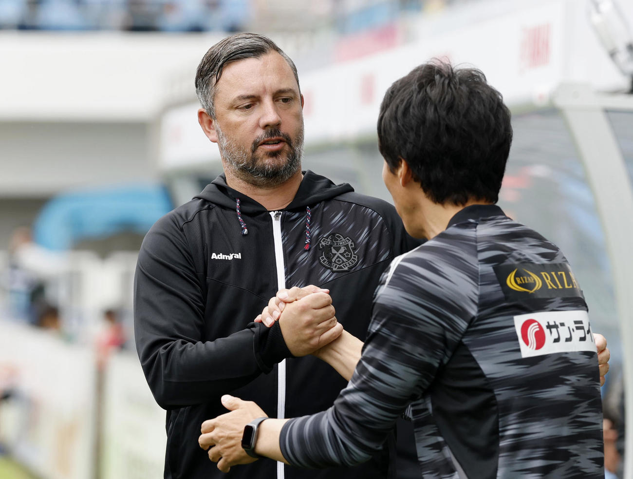 試合前、湘南山口監督と握手を交わす磐田ハッチンソン監督（共同）