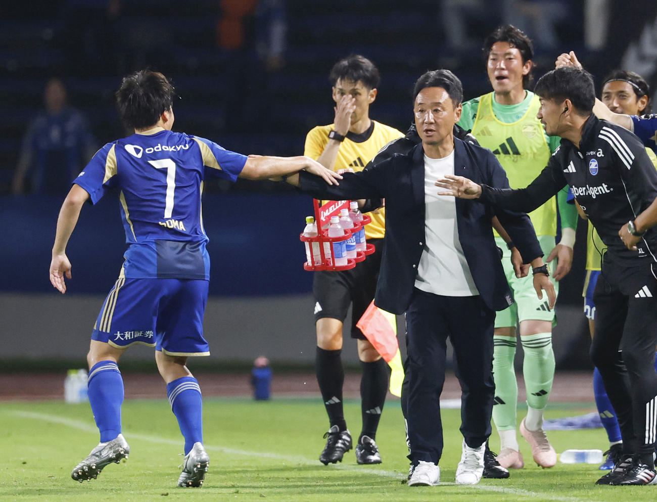 試合終了間際、決勝PKを決めた相馬とタッチを交わす町田・黒田監督（共同）