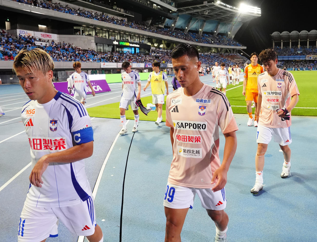 川崎F対新潟　試合後、サポーターへあいさつに向かう新潟の堀米（手前左）と小野（同右）ら（撮影・江口和貴）