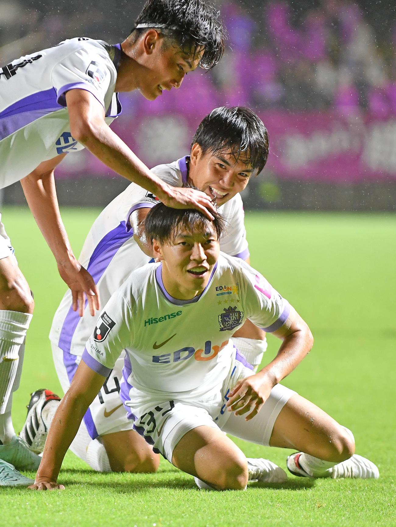 ゴールを決めた広島中村（手前）は滑り込む。奥は田中