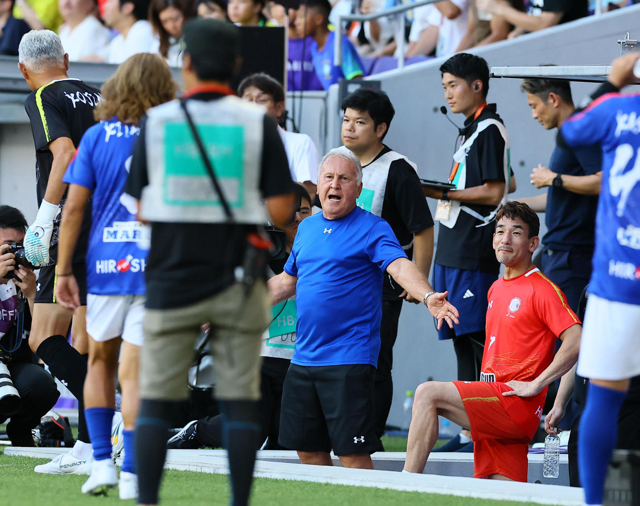 ワールドレジェンド対ジャパンレジェンド　後半、ベンチから試合を見つめるジャパンレジェンドのジーコ監督（左）とワールドレジェンドの中田英寿監督（撮影・藤尾明華）