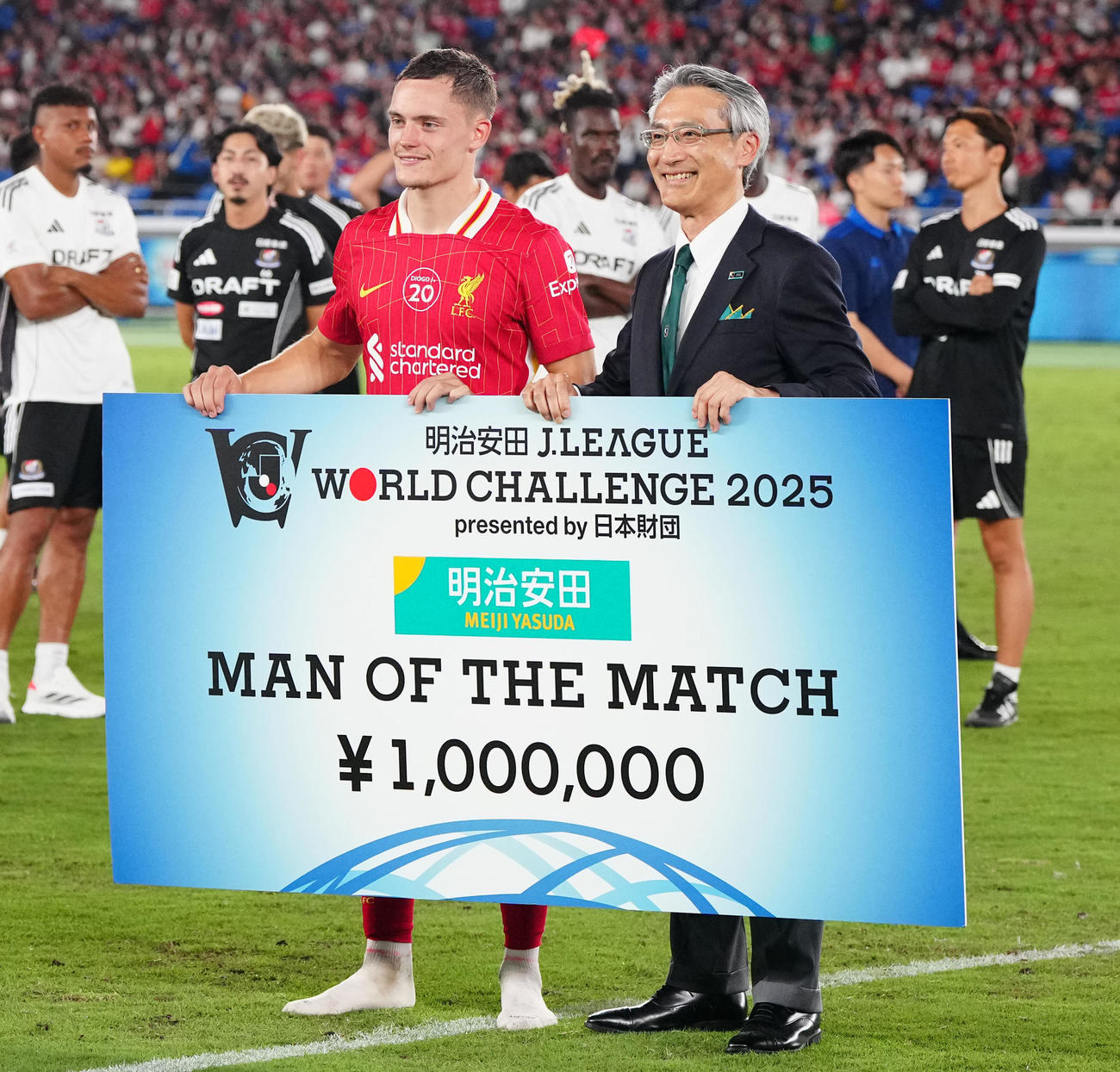 横浜対リバプール　試合後、表彰を受けるリバプール・ビルツ（左）。右は明治安田生命永島社長（撮影・江口和貴）