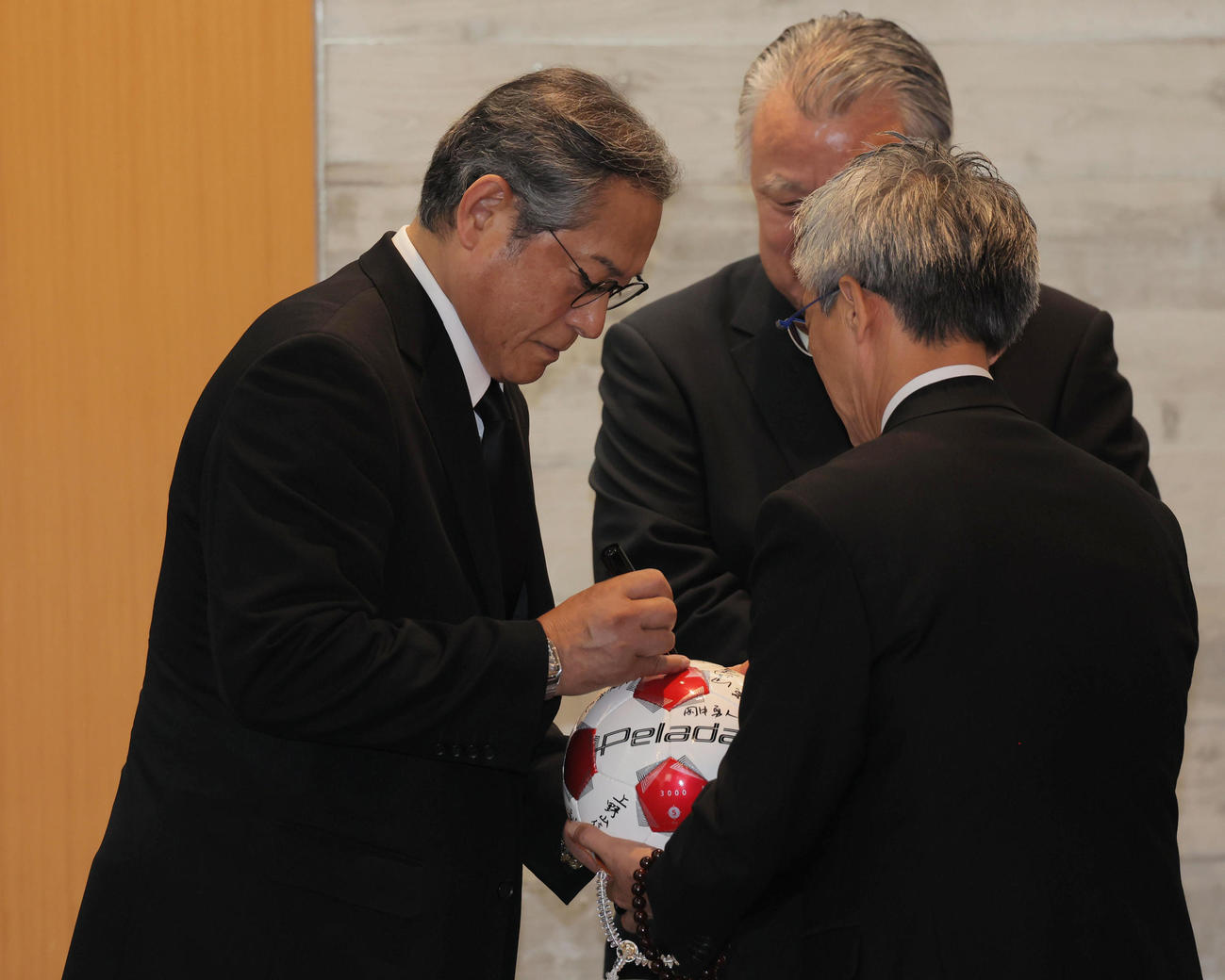 釜本邦茂さんの葬儀で棺に入れるボールにサインする松平健（撮影・宮崎幸一）