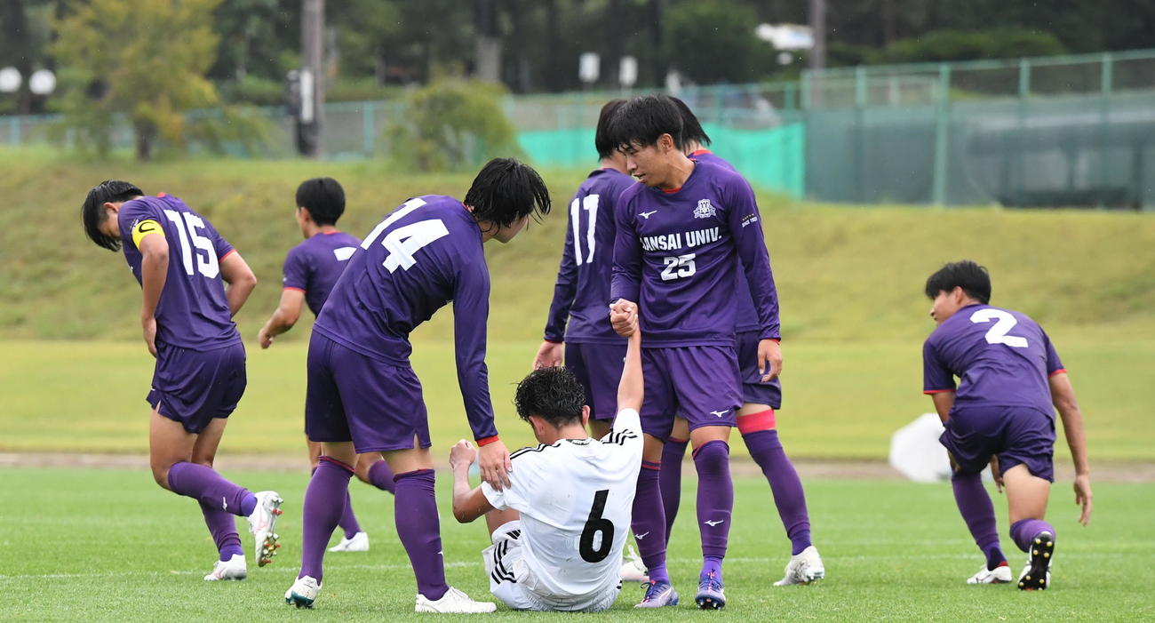 試合後、関西大の選手たちの手を借りて立ち上がる新潟医療福祉大・向井（背番号6）（撮影・小林忠）