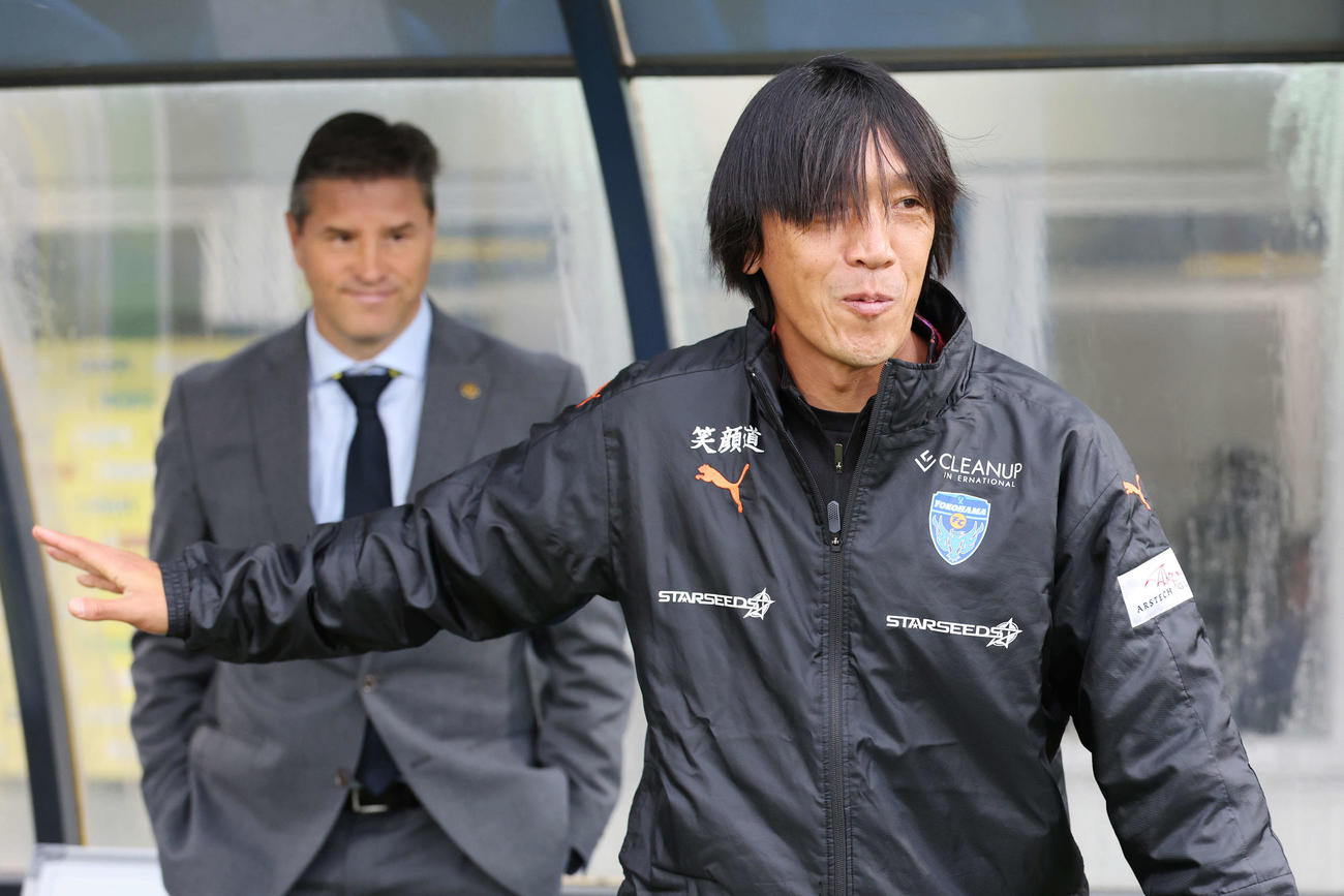 柏対横浜FC　試合前、柏ロドリゲス監督（後方）とあいさつを交わした横浜FC中村コーチ（撮影・宮地輝）