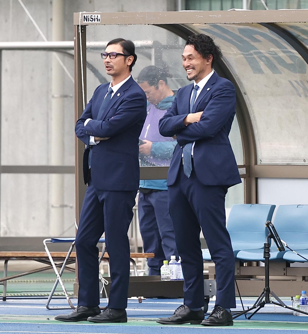 水戸対大宮　試合前、ウオーミングアップを見つめる水戸森監督（左）と本間氏（撮影・宮地輝）