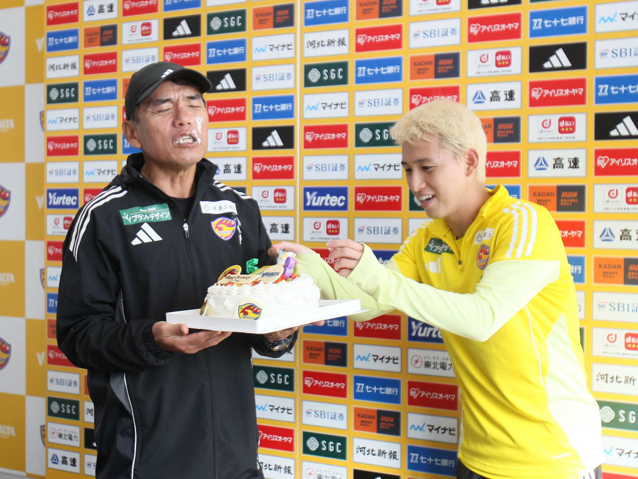 J2仙台森山監督（左）に誕生日ケーキを食べさようとするFW荒木（撮影・高橋香奈）