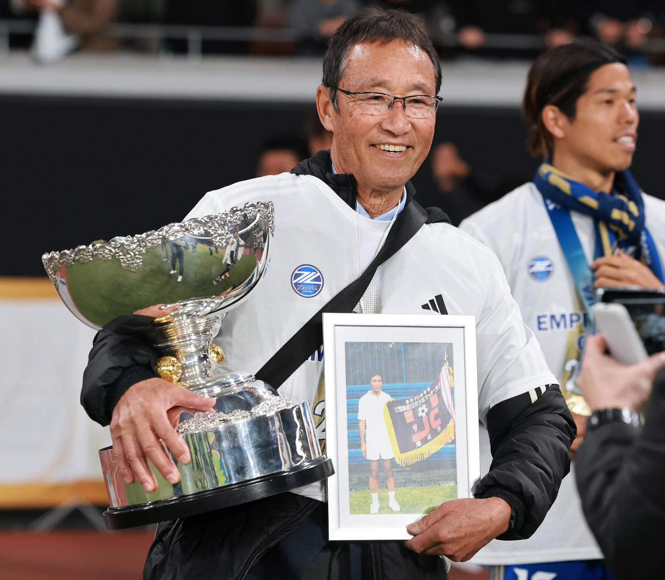 町田対神戸　初代代表の故・重田貞夫さんの写真と天皇杯を手に喜ぶ町田守屋相談役（撮影・野上伸悟）