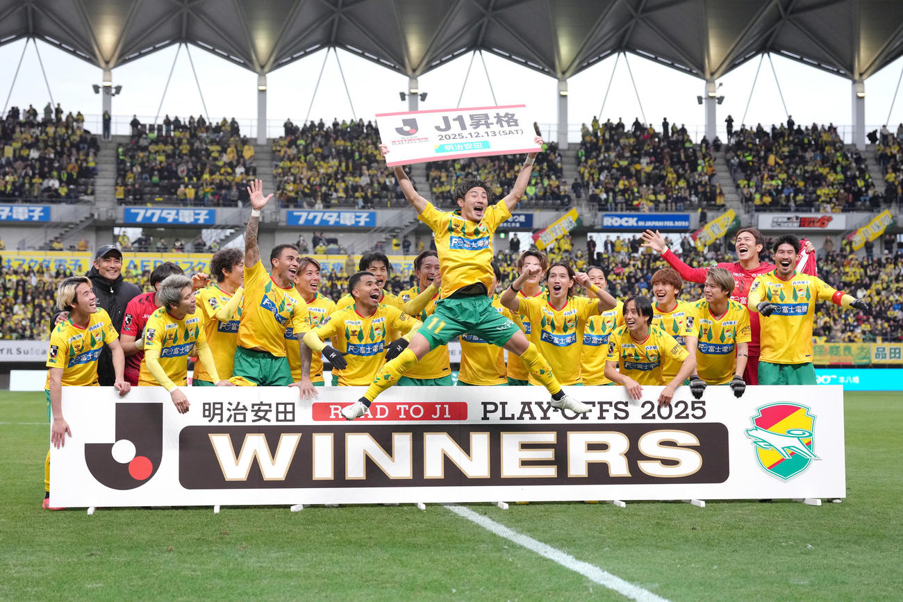 J1昇格を決め、大ジャンプで記念のボードを掲げる千葉米倉（中央）（撮影・足立雅史）