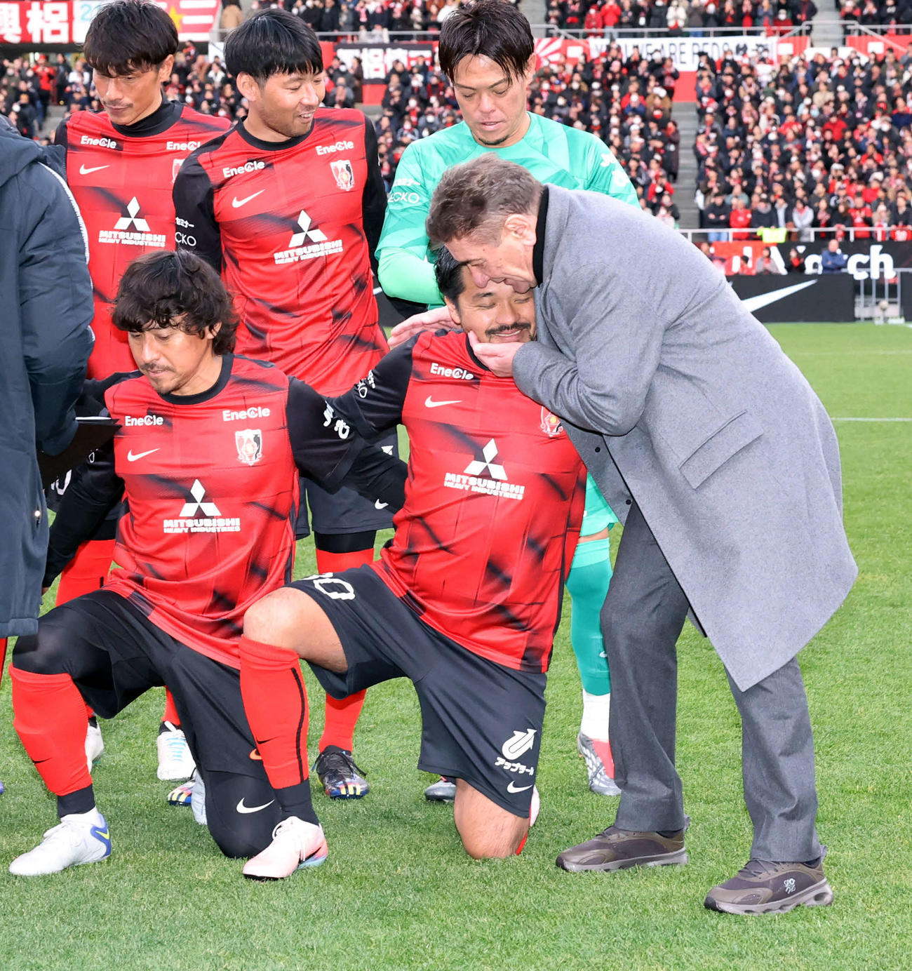 興梠慎三引退試合　浦和対鹿島　試合前の集合写真後、この日浦和を率いたペトロヴィッチ監督（右）から抱擁される興梠慎三さん（撮影・浅見桂子）