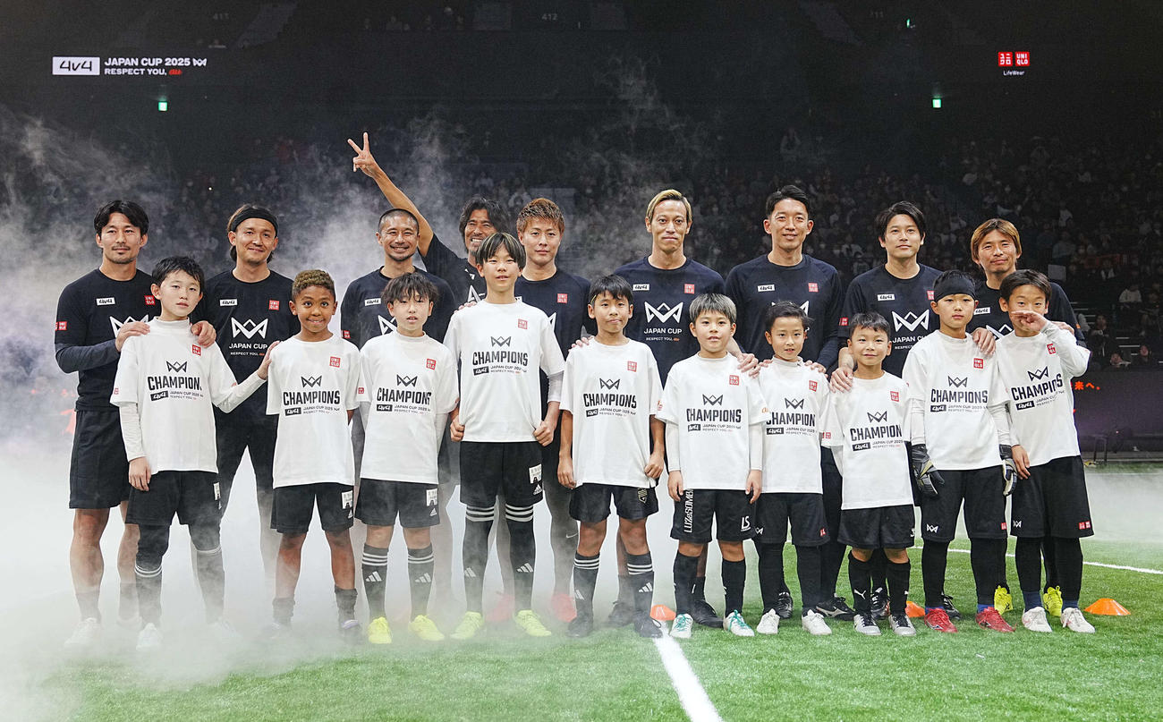 「4v4 JAPAN CUP2025 RESPECT YOU、　au」で子供たちと記念撮影に臨むレジェンドチームの、後列左から家長、宇佐美、坪井、中沢、柿谷、本田、権田、内田、乾（撮影・小沢裕）