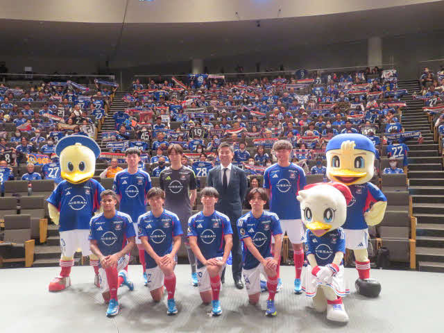 横浜新体制発表会でファン・サポーターをバックに記念撮影に収まる大島秀夫監督（後列右から2人目）と新加入選手たち