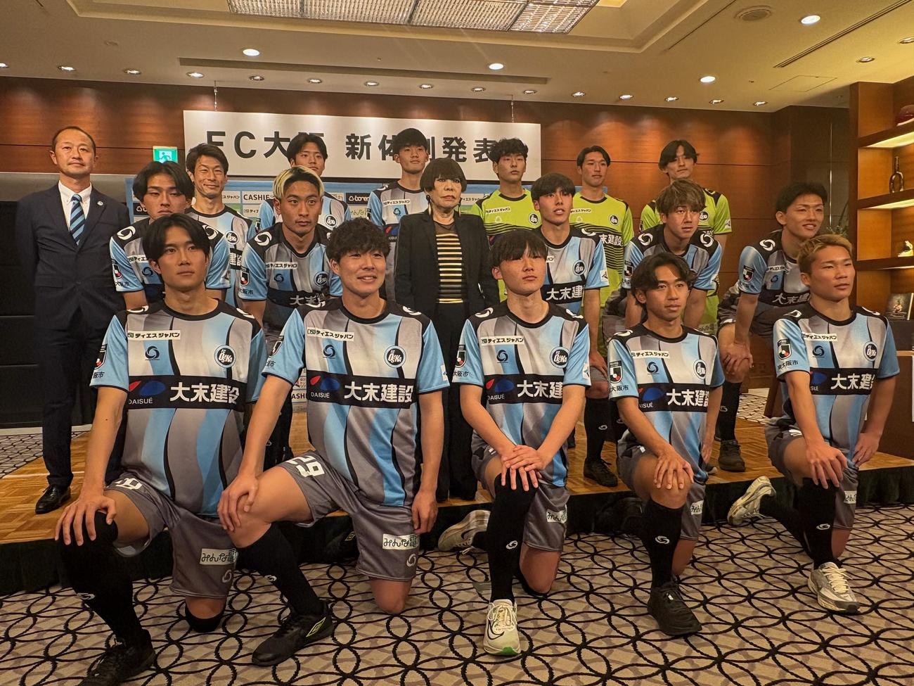 新体制発表会で集合写真に収まるFC大阪の新加入選手とユニホームをデザインしたコシノジュンコさん（中央）