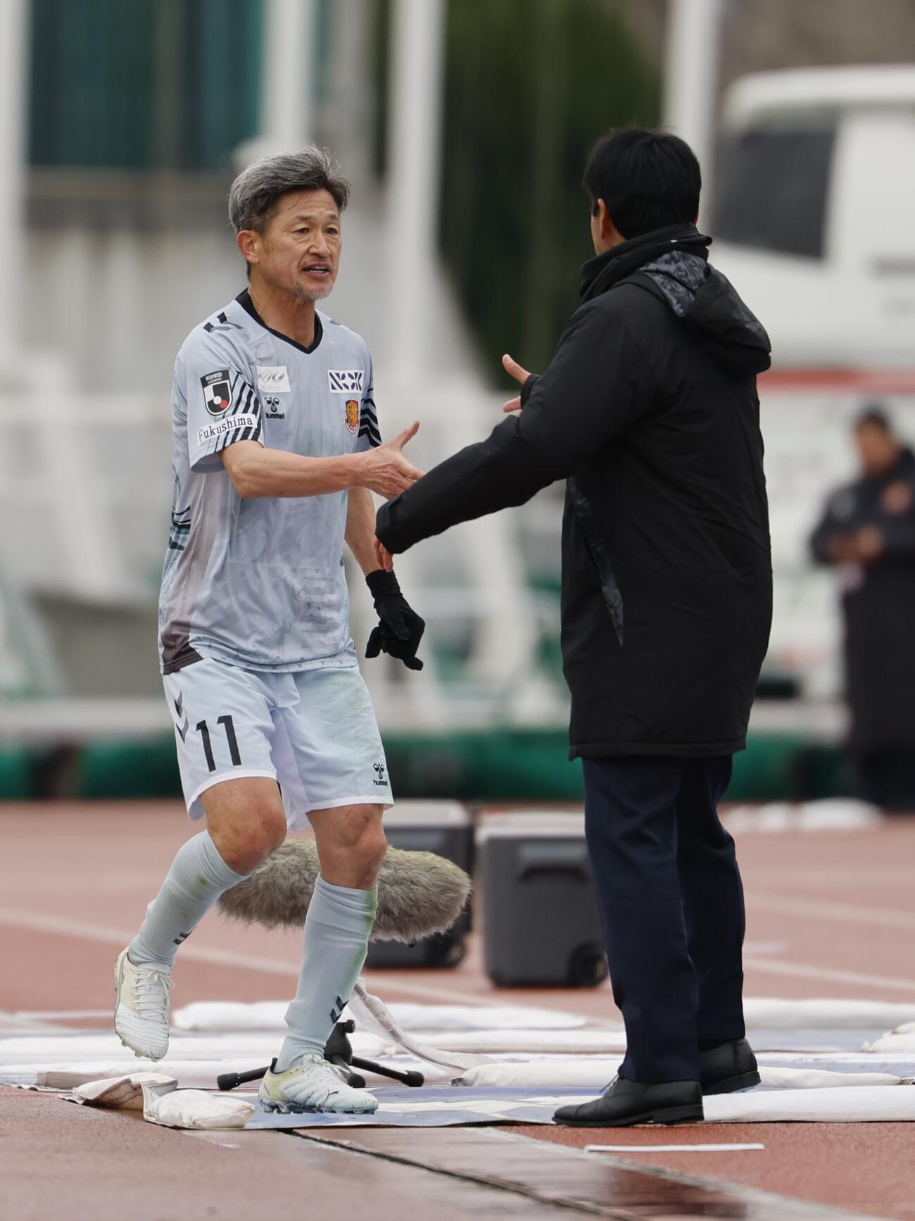 甲府対福島　前半、選手交代時に甲府渋谷監督と握手をする福島カズ（左）（撮影・山本朝陽）