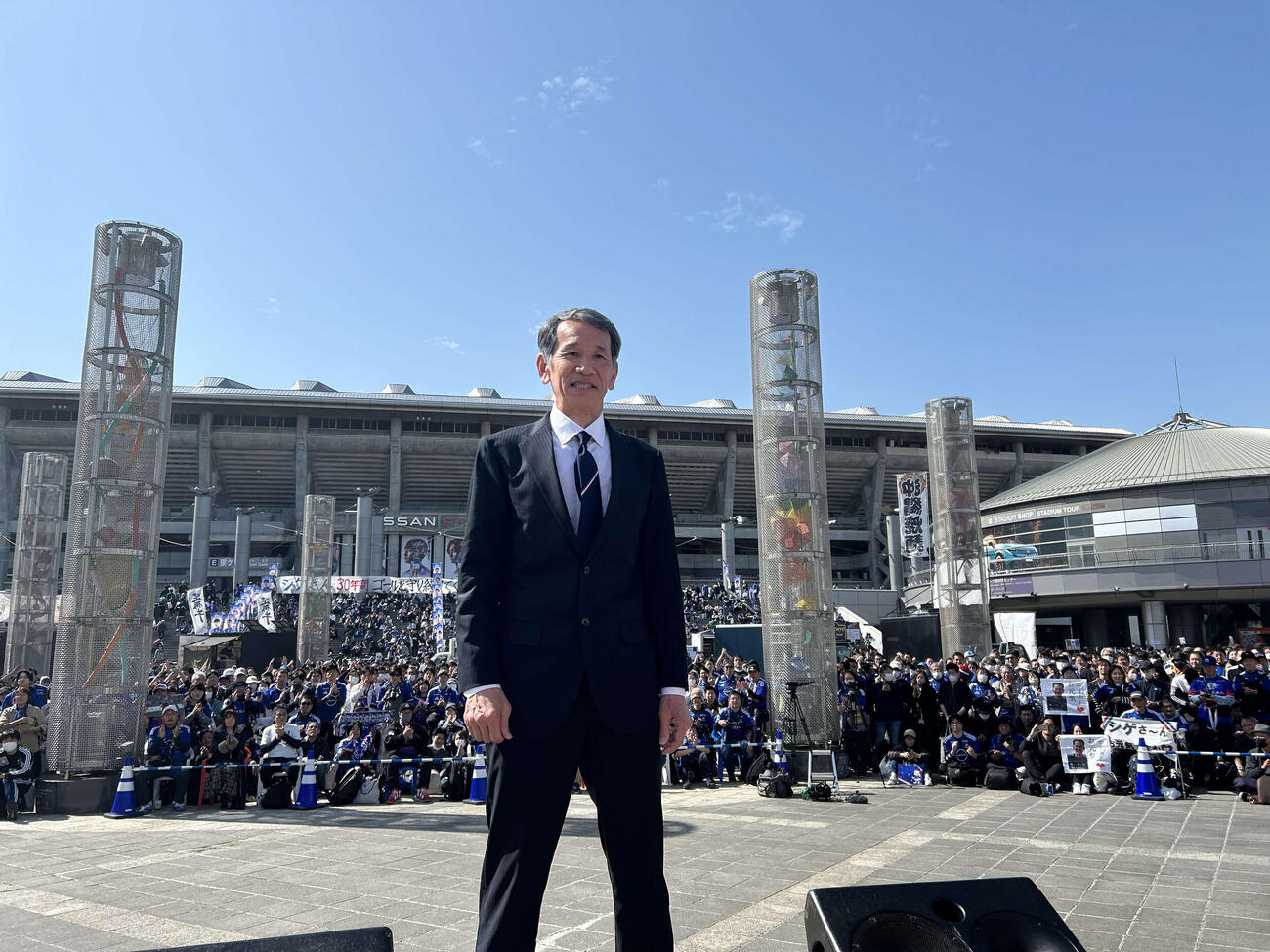 サポーターをバックに記念撮影に収まる松永成立さん