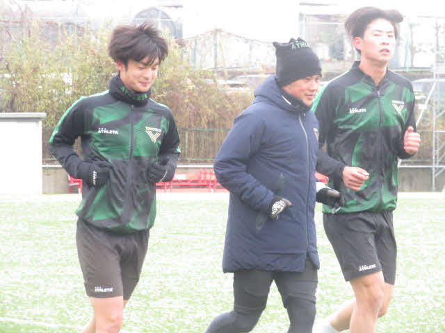 雪が積もったグラウンドでランニングする東京VのMF仲山獅恩（左）、奈良輪雄太コーチ（中）、FW大藤颯太