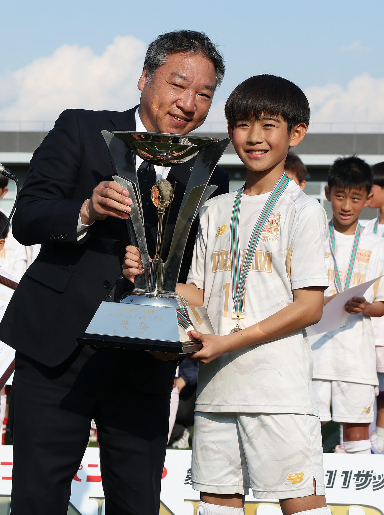 フジパンCUPで優勝し、フジパン株式会社枚方工場長川坂昌史氏（左）からトロフィーを受け取るDREAM FC曽根健介（撮影・前田充）