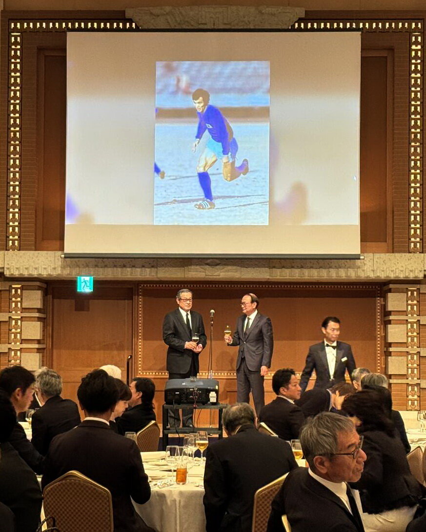 数々の写真が公開された釜本邦茂さん一周忌であいさつする出席者（家族提供）