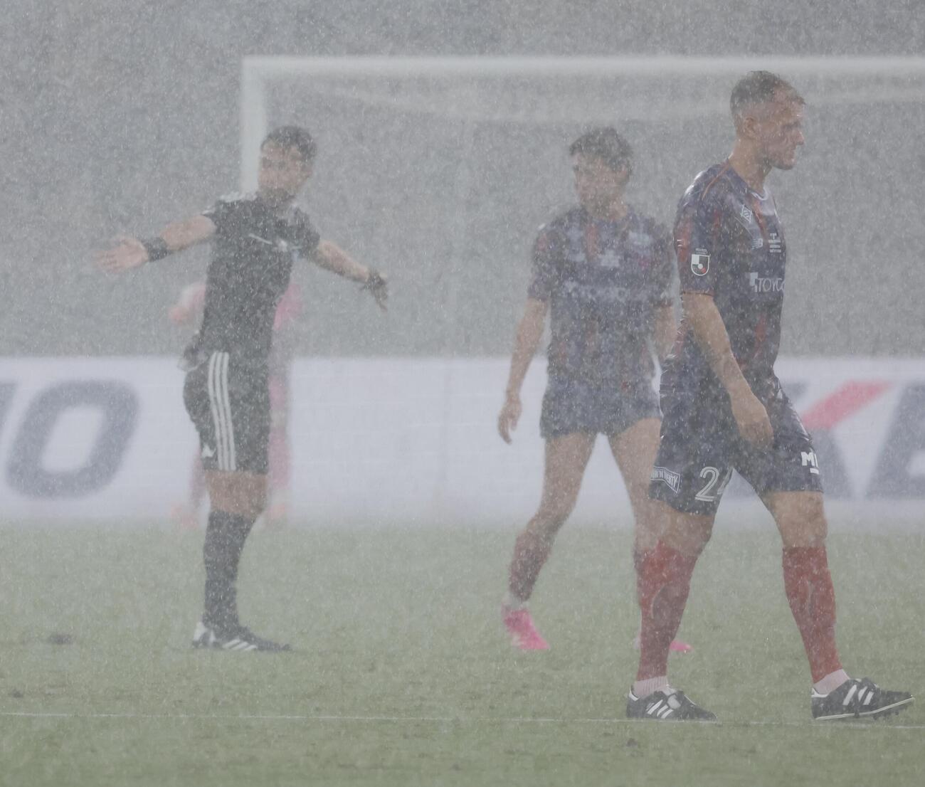 東京対ドルトムント　前半、雷雨中断を指示する高崎航地主審（左）（撮影・山本朝陽）