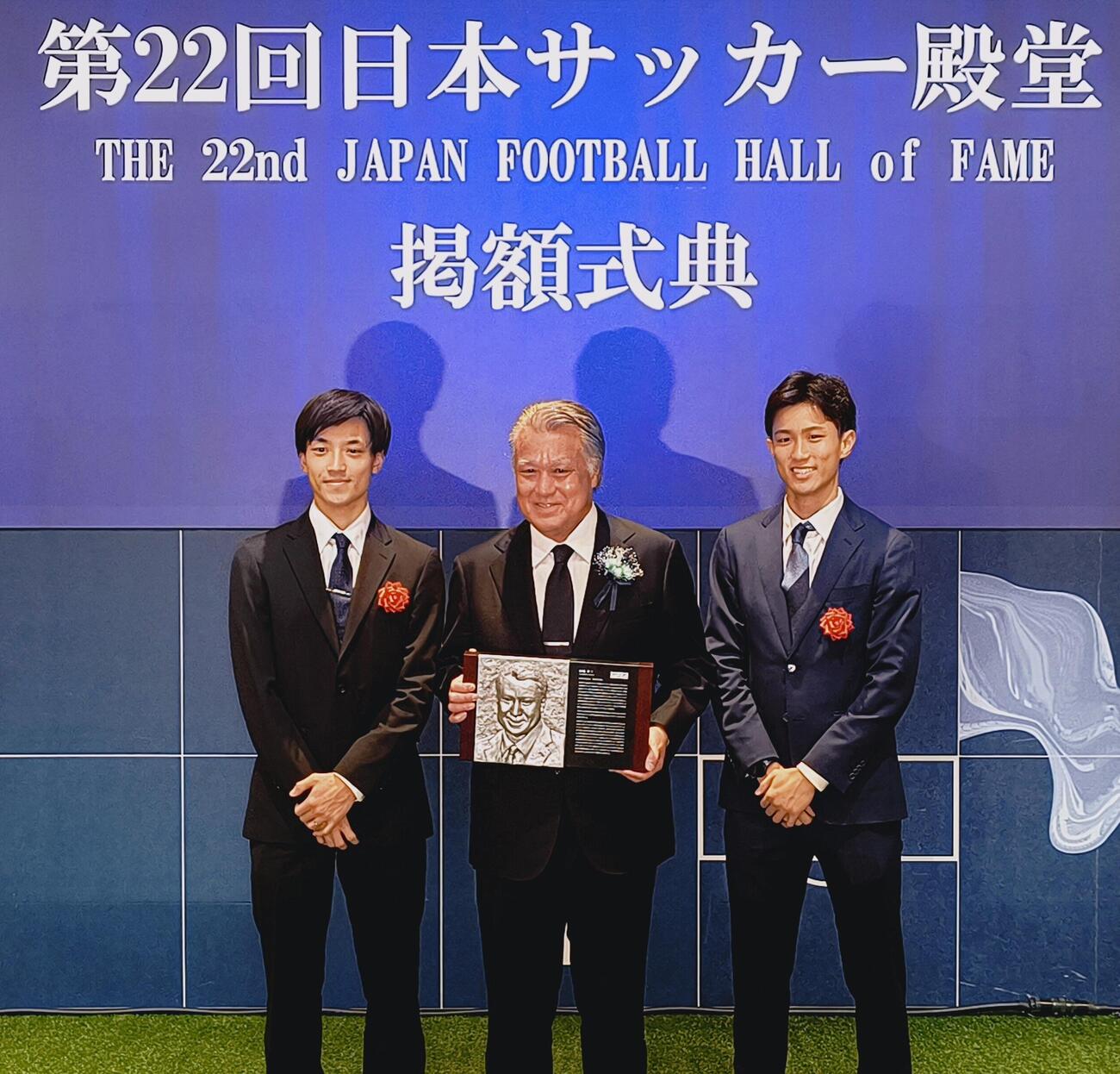 日本サッカー殿堂掲額式典でレリーフを手に笑顔で記念撮影する田嶋幸三氏（中央）。左は長男の凜太郎さん、右は次男の翔さん（撮影・木下淳）