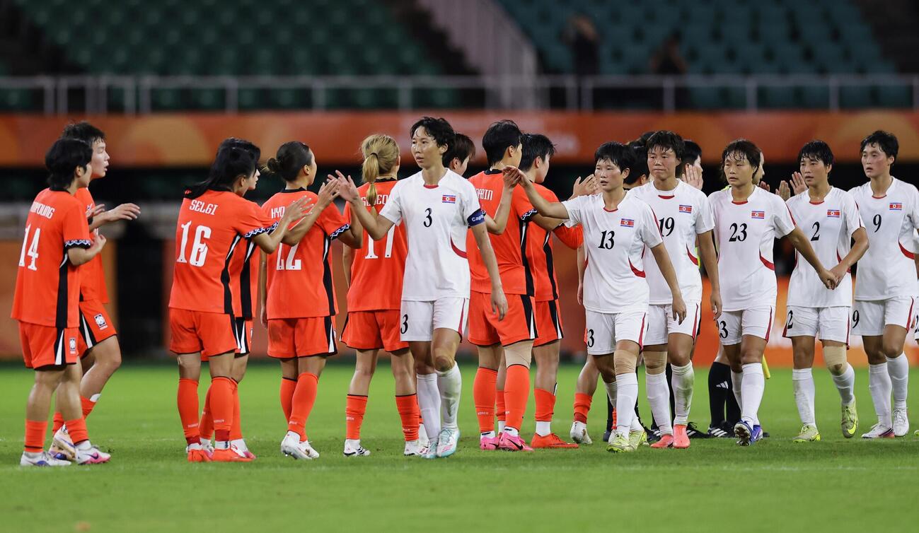 サッカー女子で引き分け、健闘をたたえ合う韓国（左）と北朝鮮の選手たち（共同）