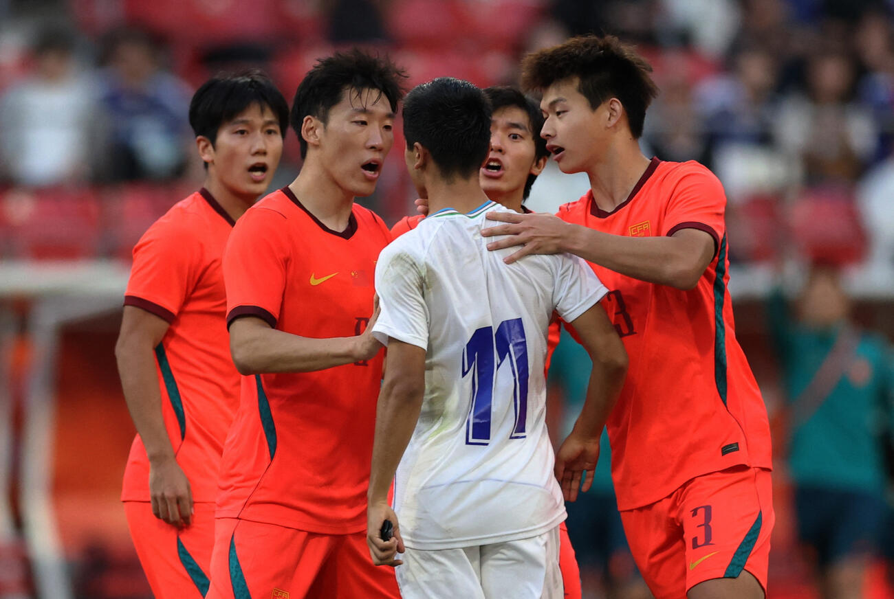 アジア大会3位決定戦　PK戦の最中、ウズベキスタンのアシルベク・ジュマエフ（中央）が、中国の劉浩凡と朱晨傑と激突する（ロイター）