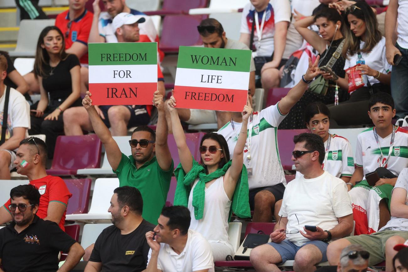 スタジアム内で「イランに自由を」「女性の命の自由」と書いたサインを掲げるイランサポーター（ロイター）