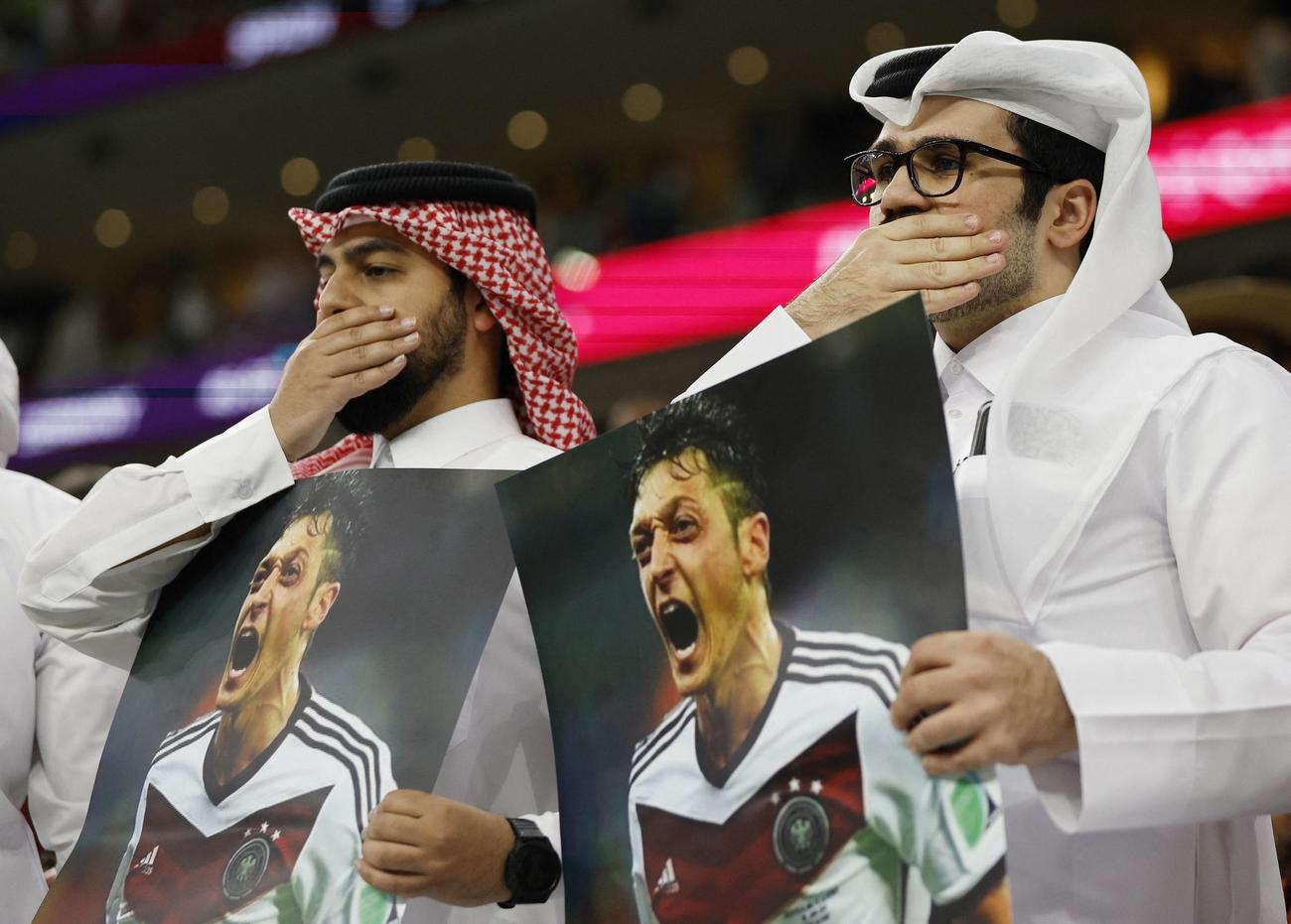 元ドイツ代表MFエジルの写真を掲げ、口を手でふさぐカタールのファン（ロイター）｜