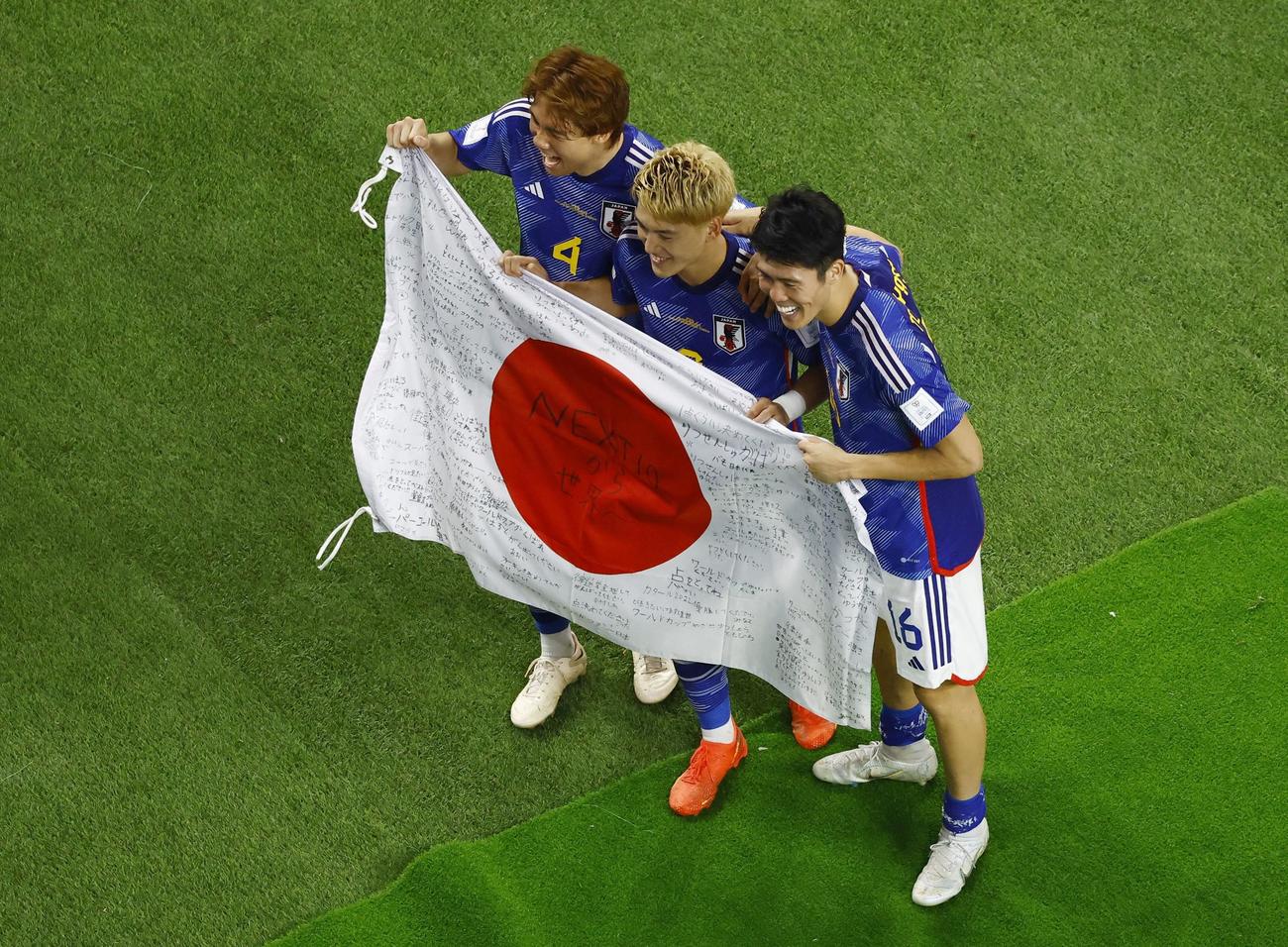 国旗をかかげ喜ぶ、左から板倉、堂安、冨安の3選手（ロイター）