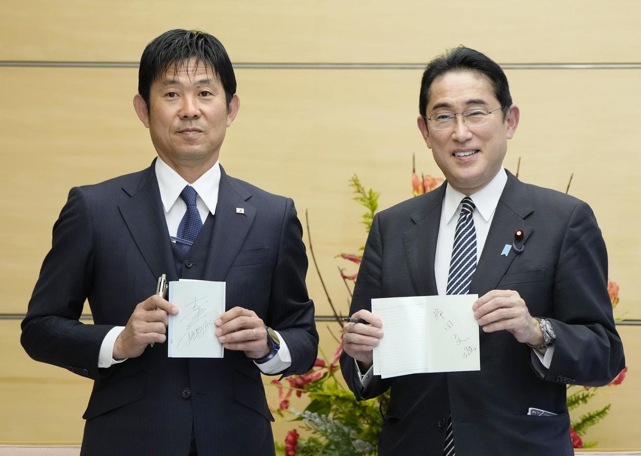 日本代表メンバーと面会し、森保一監督（左）とお互いにサインした手帳を交換して笑顔の岸田首相（共同）