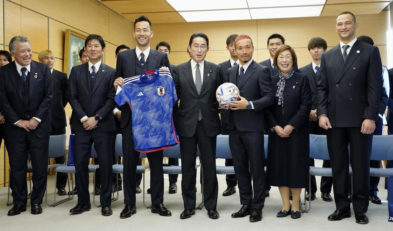 日本代表の（左から2人目から）森保一監督、主将の吉田麻也選手（1人おいて）長友佑都選手らメンバーと面会し、記念写真に納まる岸田首相（中央）＝8日午後、首相官邸（共同）