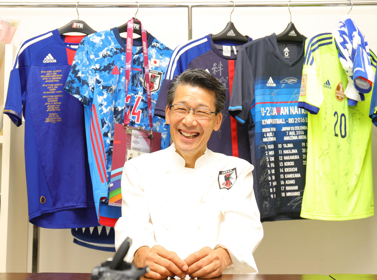 2022年8月30日、笑顔で取材に応じるサッカー日本代表専属シェフの西芳照氏。店内には選手から贈られた多くのユニホームが飾られている