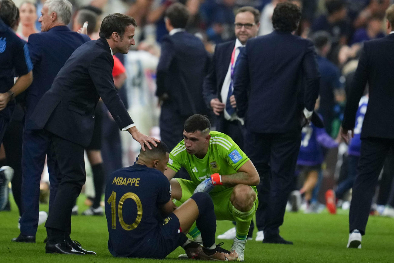 アルゼンチン対フランス　試合後、しゃがみ込むフランス・エムバペ（中央）に声をかけるマクロン大統領（左）とアルゼンチンGKのE・マルティネス（AP）