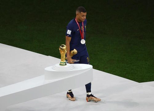 得点王に輝くも無念の表情でW杯トロフィーの横を通り過ぎるフランス・エムバペ（ロイター）