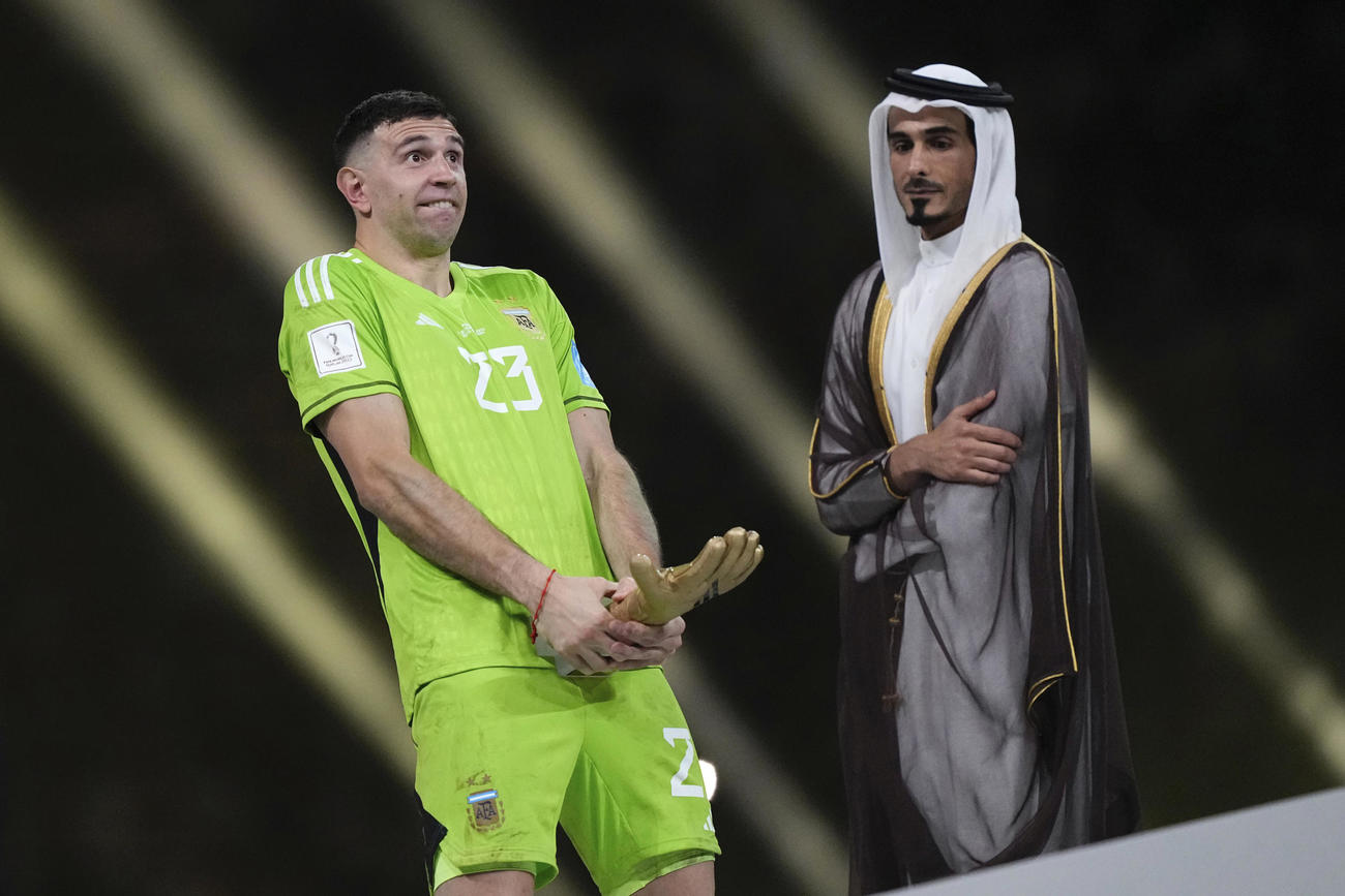 18日、W杯カタール大会で、トロフィーを手におどけたポーズを取るアルゼンチンGKのE・マルティネス（AP）