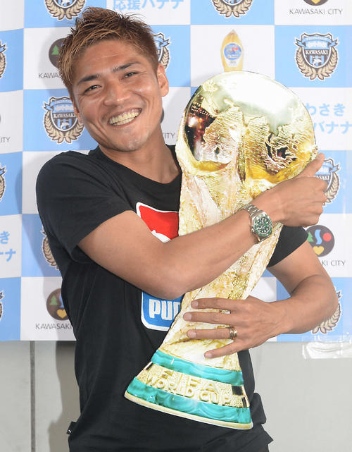 W杯代表に選出され、トロフィーの写真を抱きしめる大久保