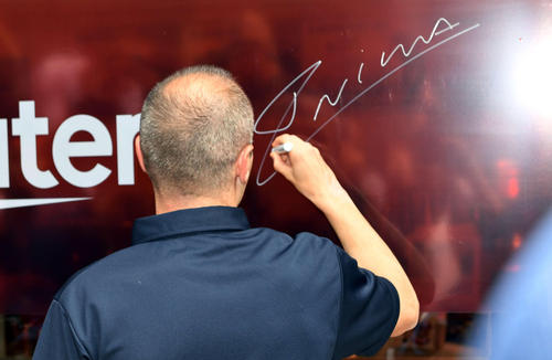 楽天カフェの壁面にサインするイニエスタ