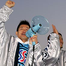 拡声器を手にサポーターと喜びを分かち合う横浜ＦＣカズ。右は先制点の根占
