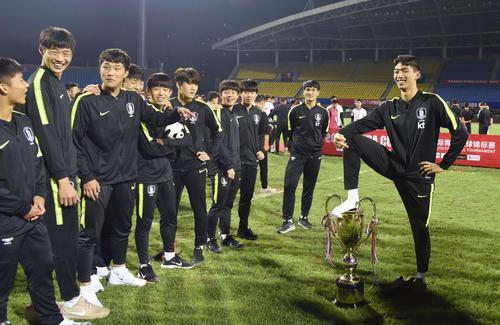 「パンダカップ」の優勝トロフィーを踏み、ポーズをとる韓国チームの選手（共同）