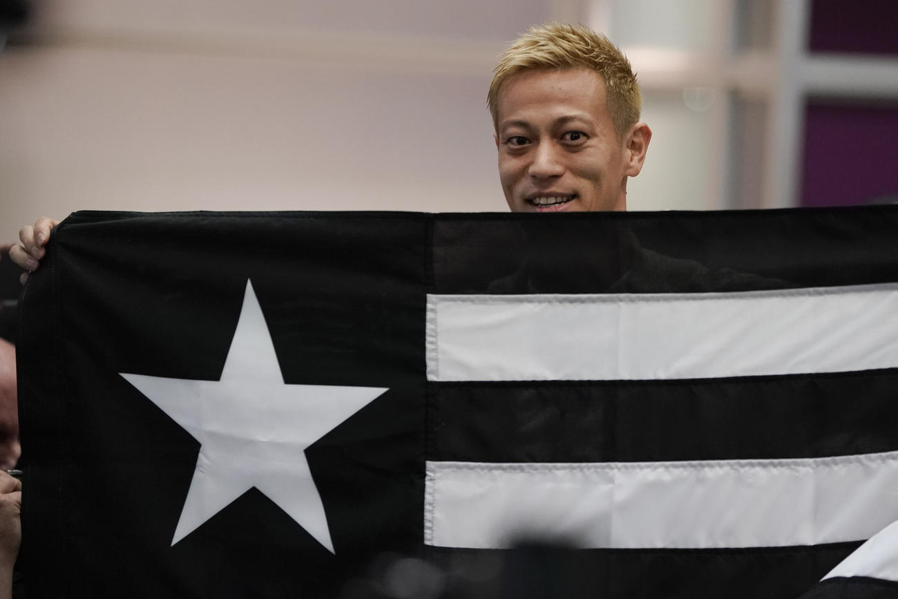 リオデジャネイロ空港でボタフォゴのチーム旗を掲げるMF本田圭佑（AP）