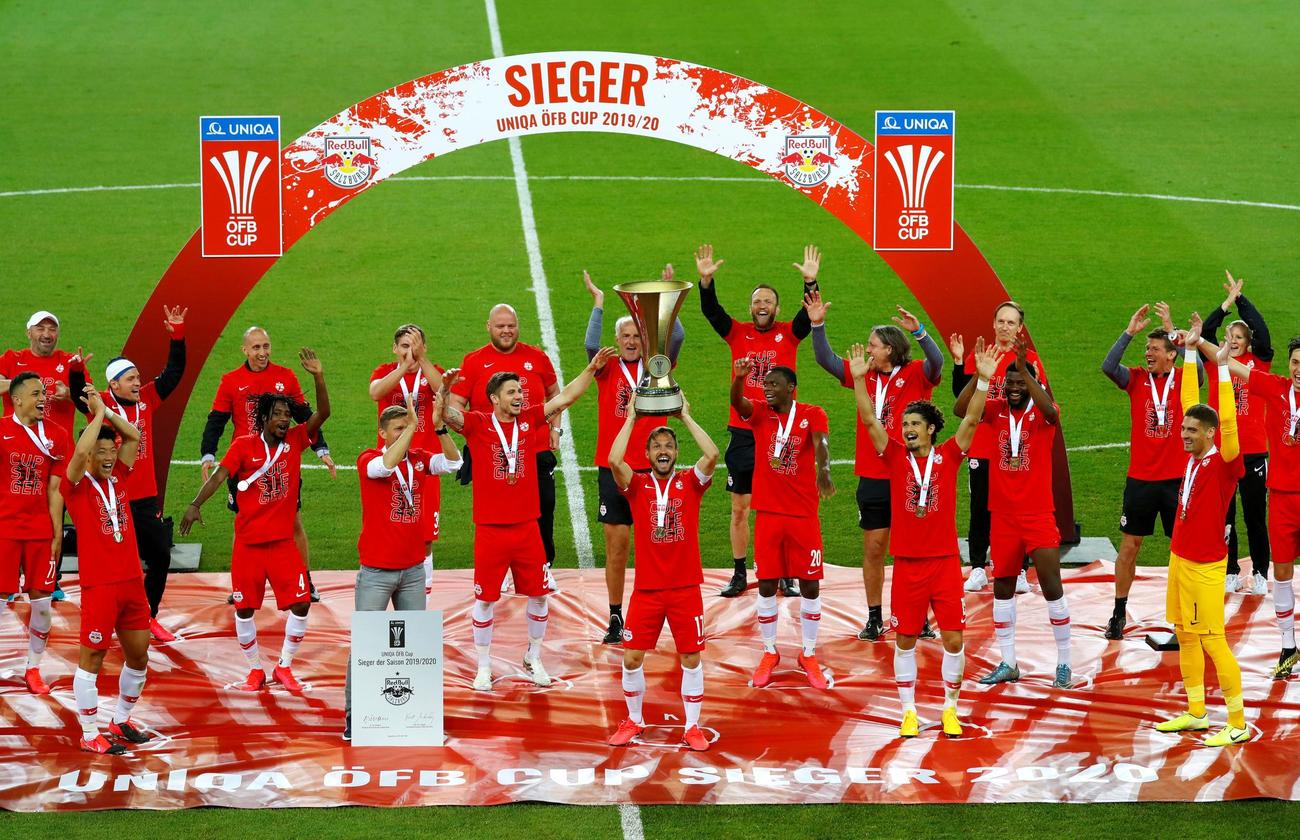 オーストリア杯で優勝し、優勝カップを掲げるザルツブルクDFウルマー（中央）。選手たちはシートに一定の間隔をあけて描かれた円の上に立って喜びを表した（ロイター）