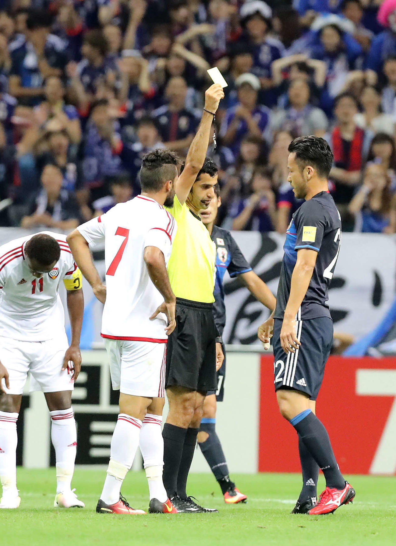 2016年9月1日の日本対UAE戦で吉田（右）にイエローカードを出すアブドゥルラフマン・アルジャシム審判