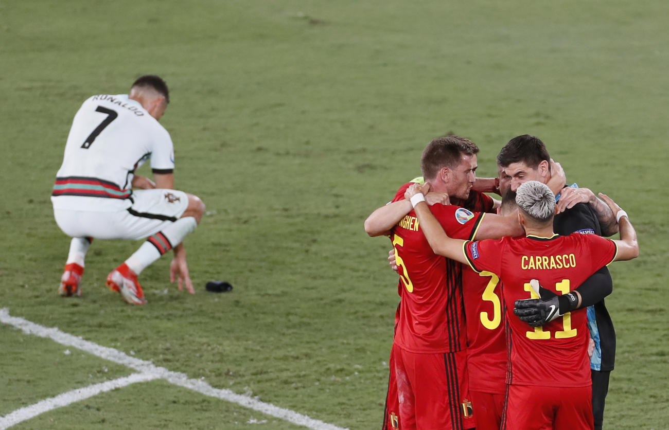 ポルトガルに勝利し喜ぶベルギーの選手たち。左は試合に敗れ、しゃがみ込むポルトガル代表ロナウド（AP）