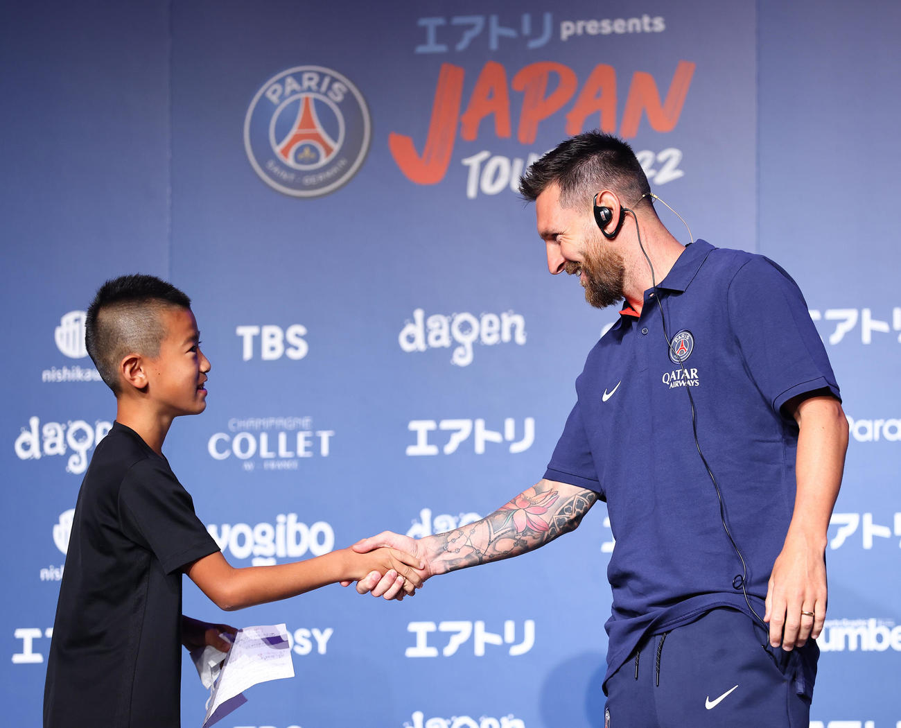 「パリサンジェルマン　ジャパンツアー2022」来日会見で当選した子どもと握手を交わすパリサンジェルマンのメッシ（右）（撮影・垰建太）