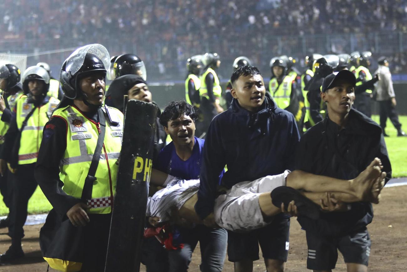 インドネシア東ジャワ州のサッカー場で、負傷した男性を運ぶ観客ら＝1日（AP＝共同）