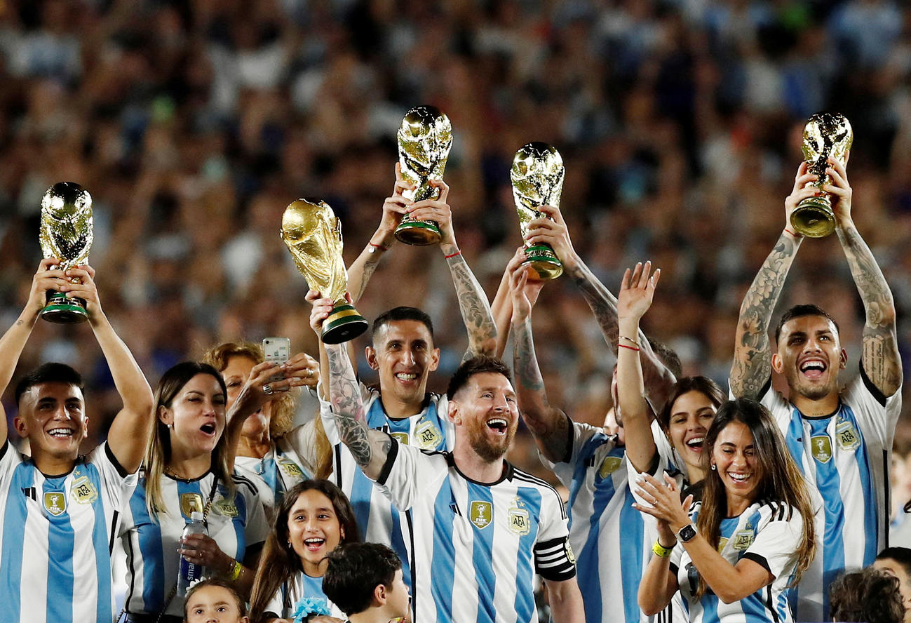 試合後、W杯優勝トロフィーを掲げ祝うメッシ（中央）らアルゼンチンの選手と家族ら（ロイター）