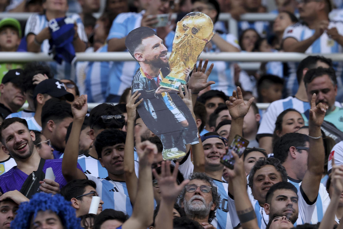 ワールドカップトロフィーとメッシの写真を手に喜ぶアルゼンチンサポーター（AP）