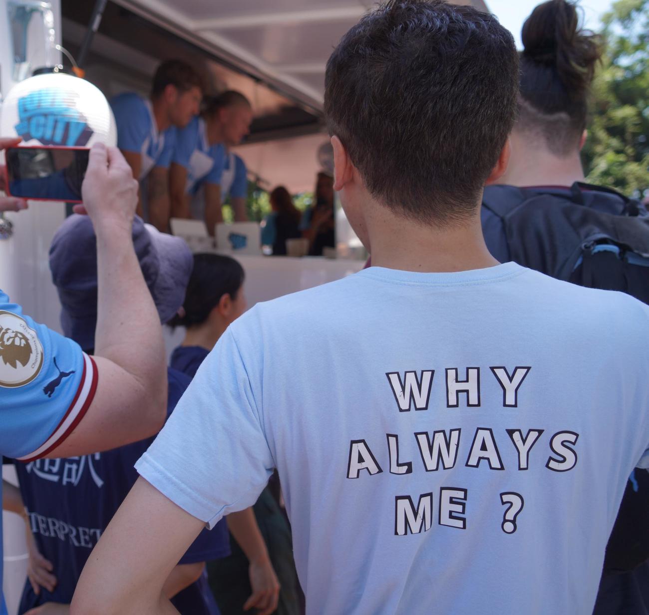 マンチェスター・シティーFWハーランドらが出席したキッチンカーイベントに「WHY ALWAYS ME？」のシャツを着用して参加した男性（撮影・佐藤成）