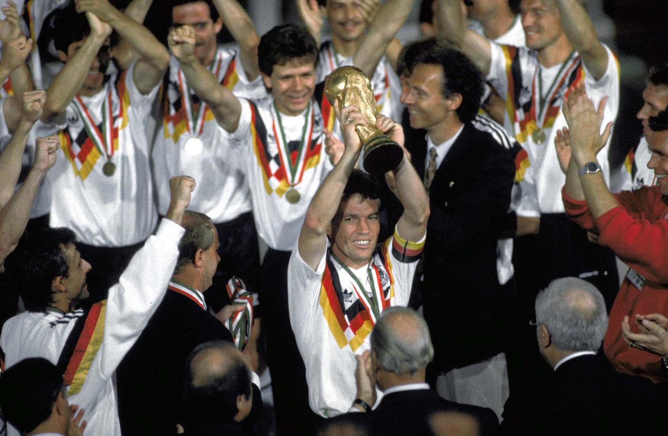1990年のW杯イタリア大会で優勝トロフィーを掲げるドイツのマテウス主将（中央）と、笑顔のベッケンバウアー監督（中央右）＝ローマ（AP＝共同）