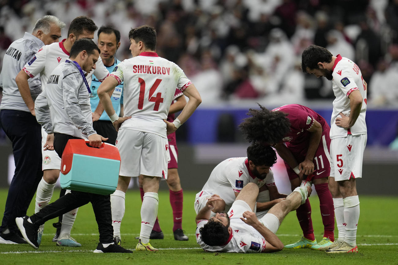 負傷したタジキスタン選手を助けるカタールのアクラム・アフィフ選手（AP）